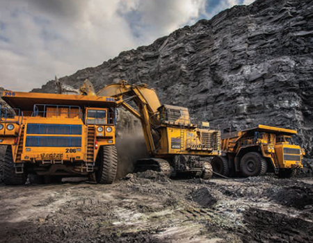 Three orange-colored heavy equipment vehicles working in a quarry.