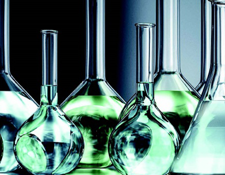 Glass laboratory containers with green liquid.