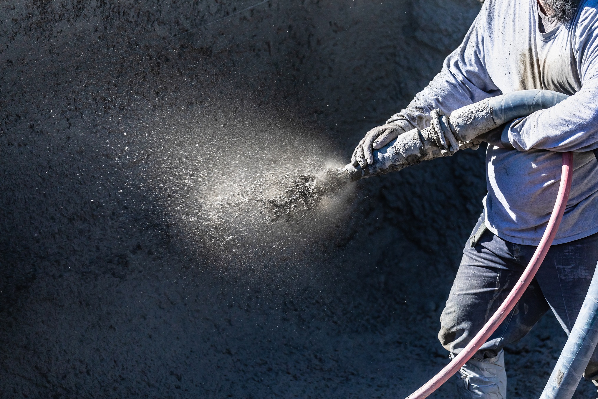 Pool Construction Worker Shooting Concrete, Shotcrete or Gunite Through Hose